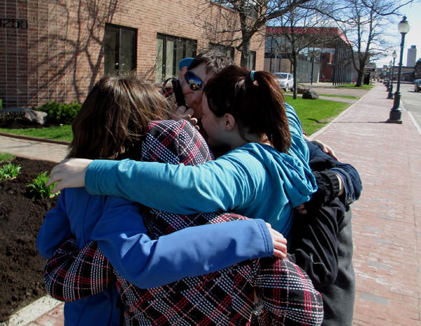 3 photos show the students gathering together into a hug that includes them all.